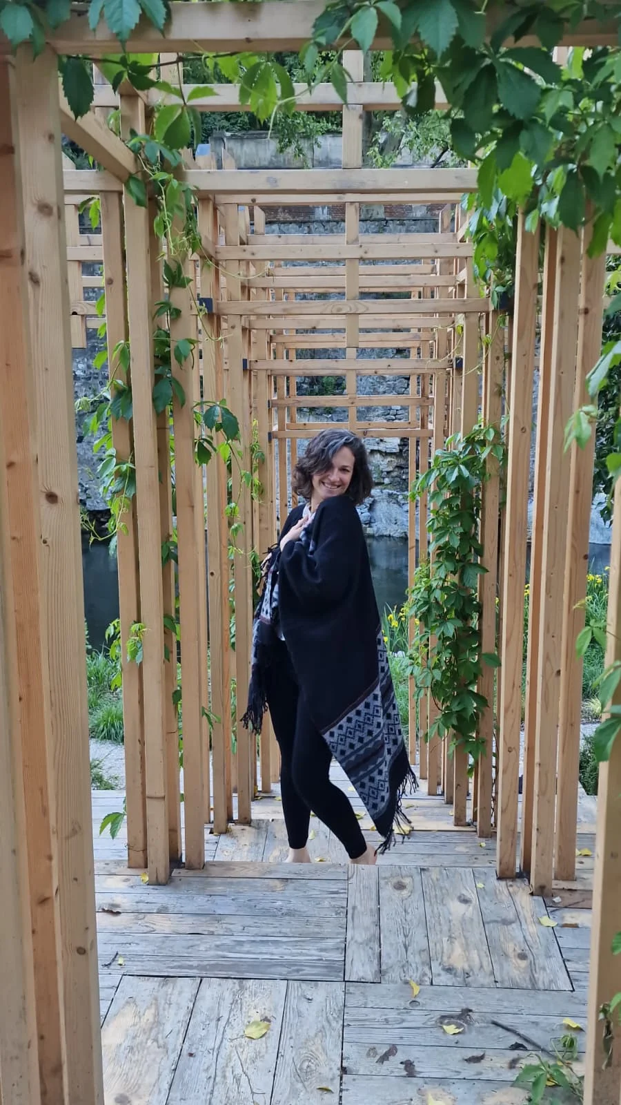 Teodora sub un foișor din lemn, înconjurată de verdeață