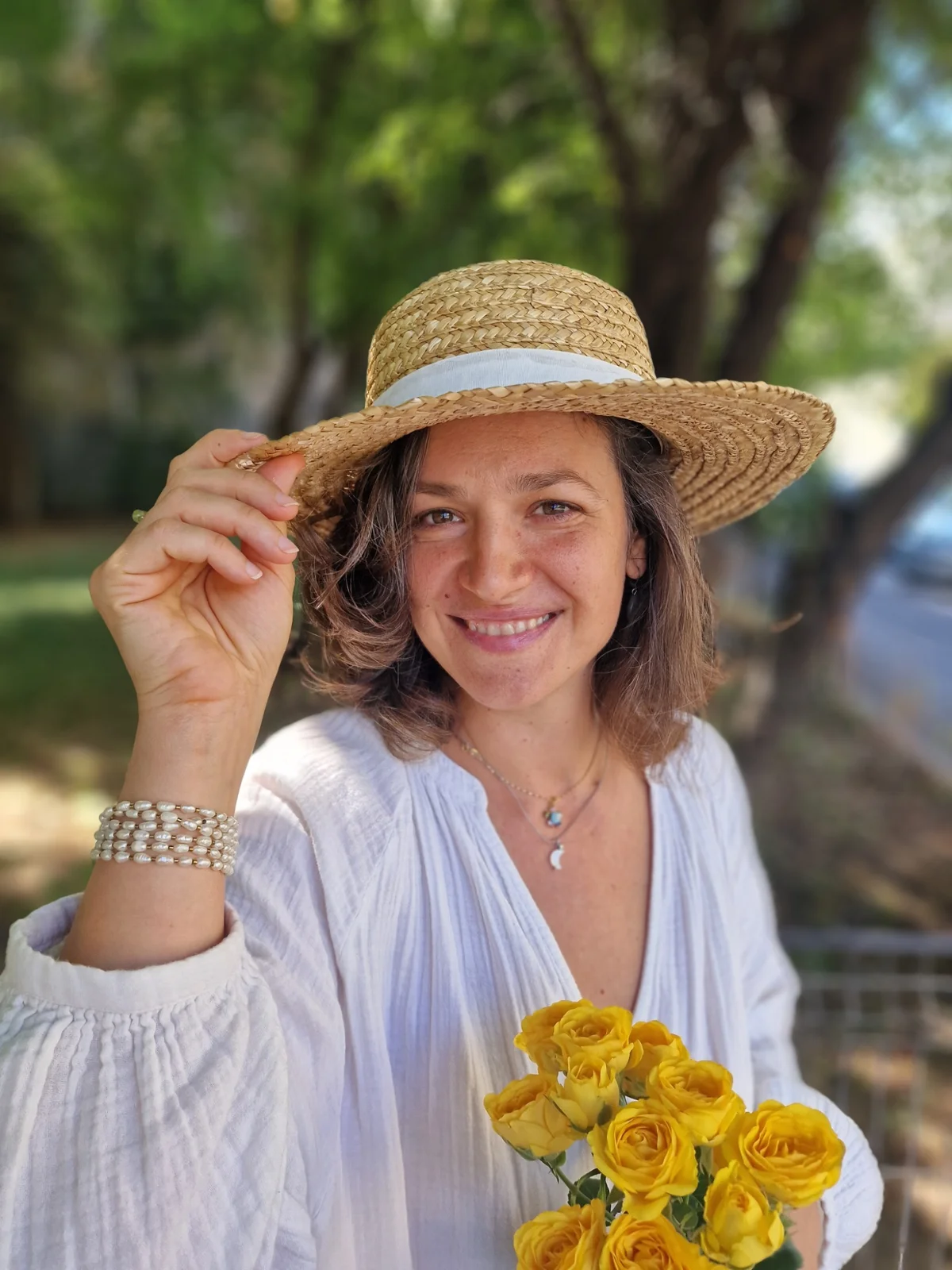 Teodora Haidu cu o pălărie de paie, ținând flori galbene